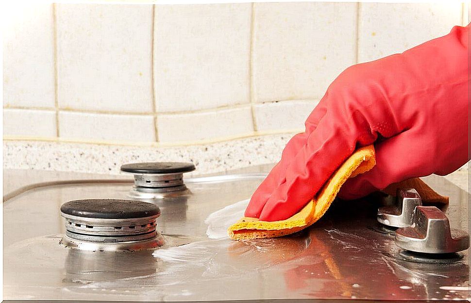 The stove is cleaned with kitchen rags and rubber gloves