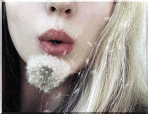 Woman blows dandelions and waits for changes