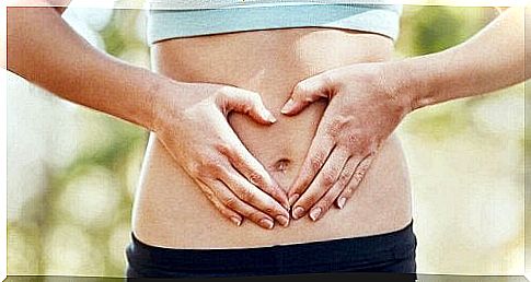 A woman holds both hands on her stomach.