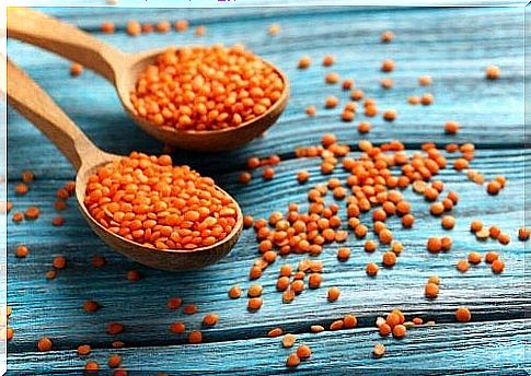 Two wooden spoons filled with red lentils.